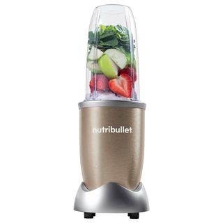 A Nutribullet Pro 900 Blender filled with ice and fruits and vegetables on a white background