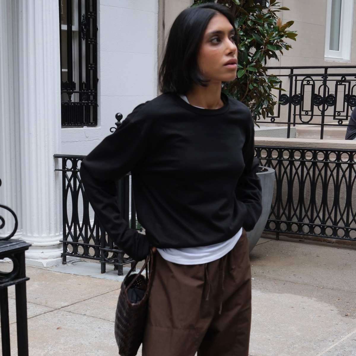 shay wears a black sweater with a white t-shirt and brown pants.