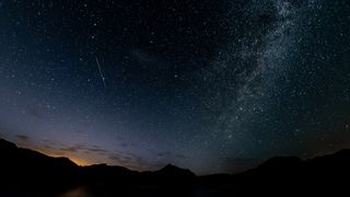 meteor streaking across a sky full of stars.