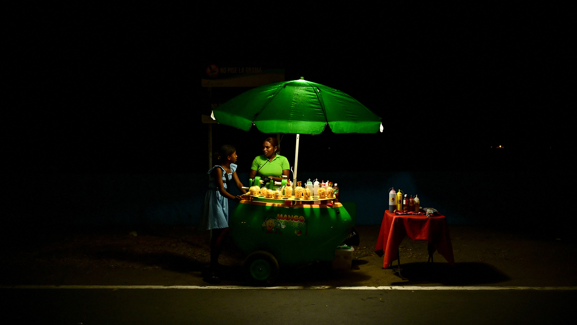 A woman sells mangoes from a street cart along a road in Panama City, Panama
