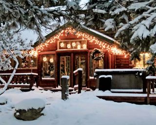 Christmas lights on wooden Colorado mountain country cabin in snow and pine trees