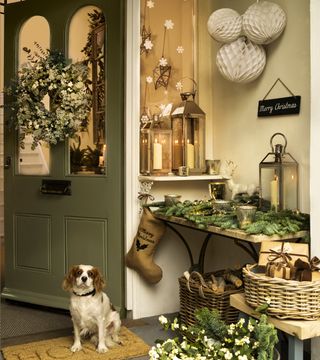 Christmas front door gold candle lanterns with wreath paper pom poms pine needles and dressed console table