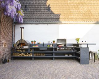 Bespoke outdoor kitchen space with grill, sink and pizza oven