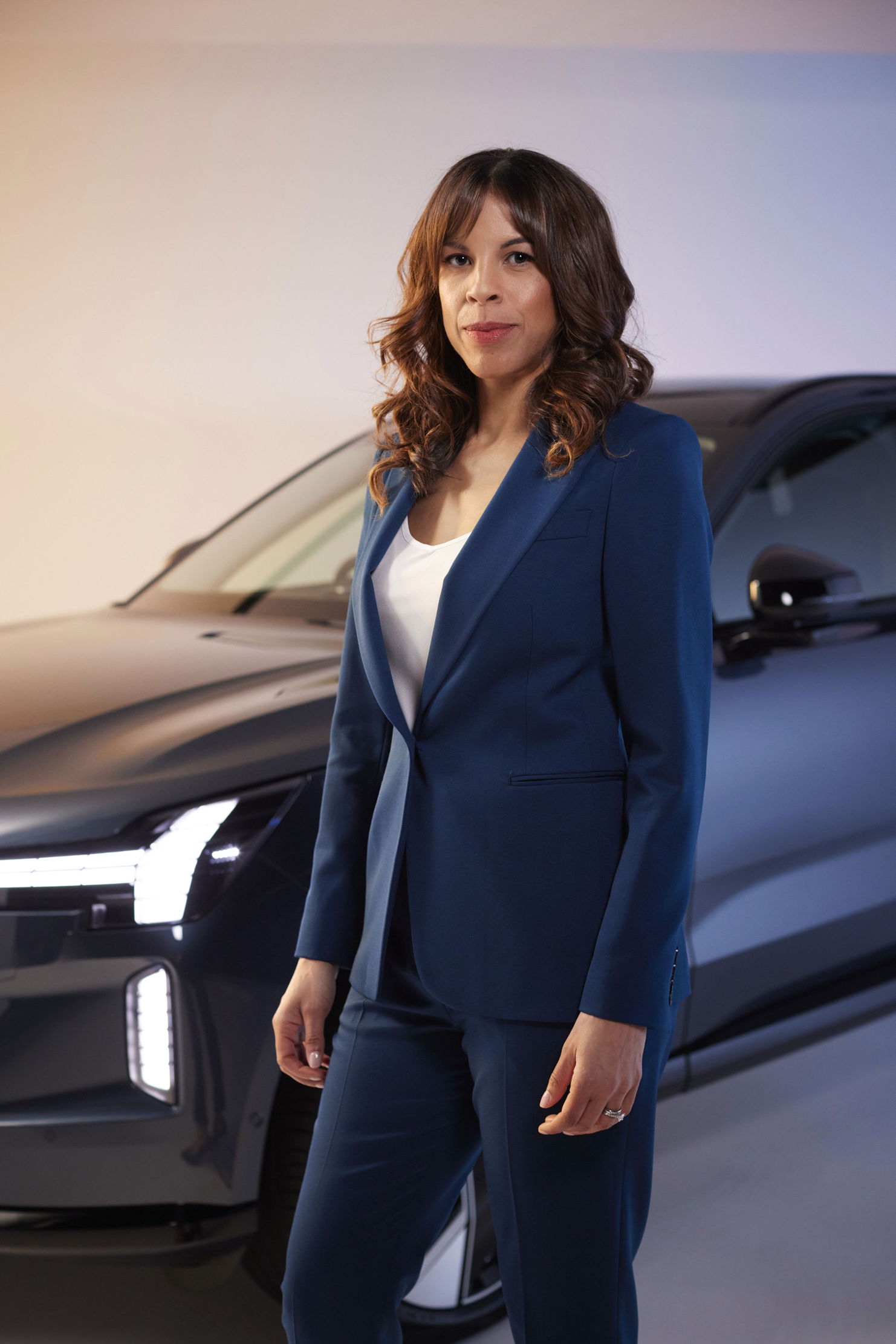 Nicole standing in front of an EX90 in a blue suit.