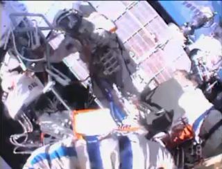 Cosmonauts Oleg Kotov, Expedition 38 commander, and Sergey Ryazanskiy perform a spacewalk outside the International Space Station on Dec. 27, 2013. One of the cosmonauts is visible in this view from the other's spacesuit helmet camera.