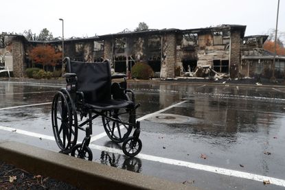 Wheelchair sits by destroyed senior living facility.