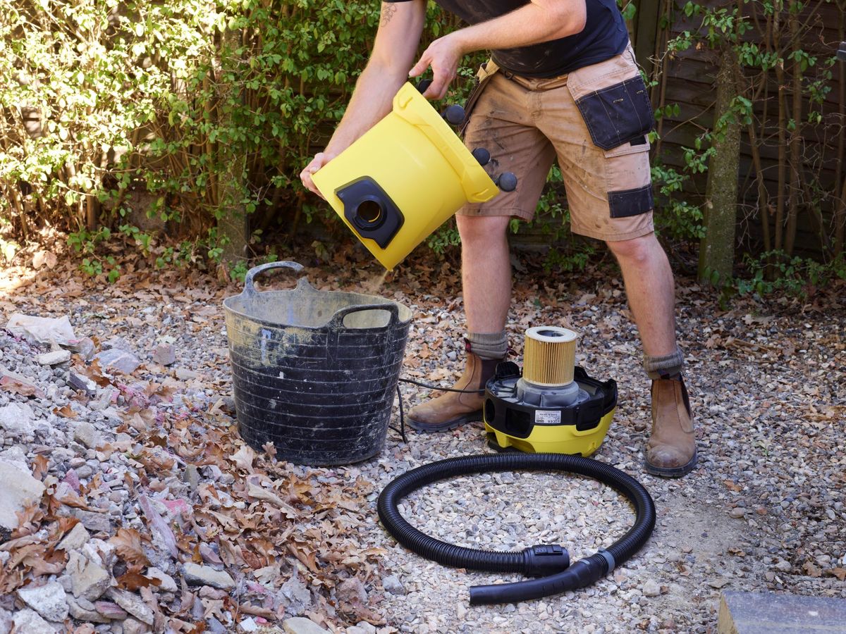 A builder empties a K&auml;rcher WD 3 vacuum cleaner