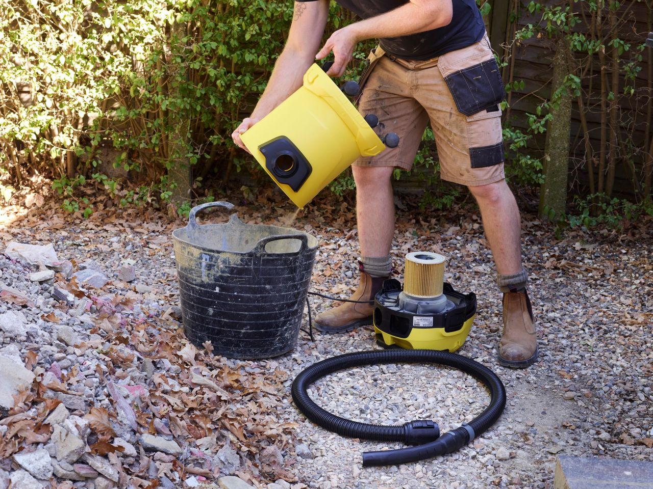 A builder empties a K&auml;rcher WD 3 vacuum cleaner