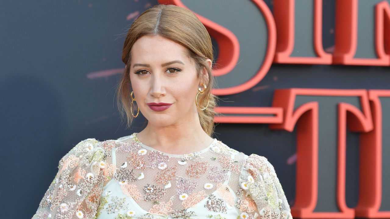 Ashley Tisdale&#039;s dining table is minimalistic and modern. Here is the actor wearing a white floral dress, with black and red lettering in the background