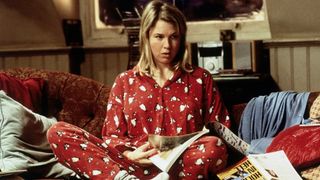 Bridget sitter i en soffa iklädd en röd julpyjamas och bläddrar i en tidning.