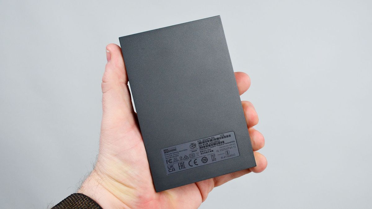A masculine hand holding a Seagate FireCuda external gaming hard drive