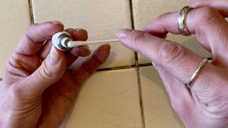 An earbuds being cleaned with a cotton swab, on beige background