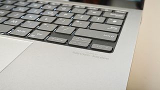 A silver ASUS Zenbook S 13 OLED laptop sitting on a wooden desk