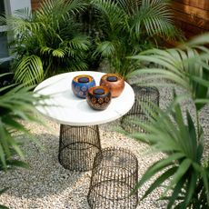Aldi's Belavi solar light fire bowls on a small table in a modern garden with foliage all around