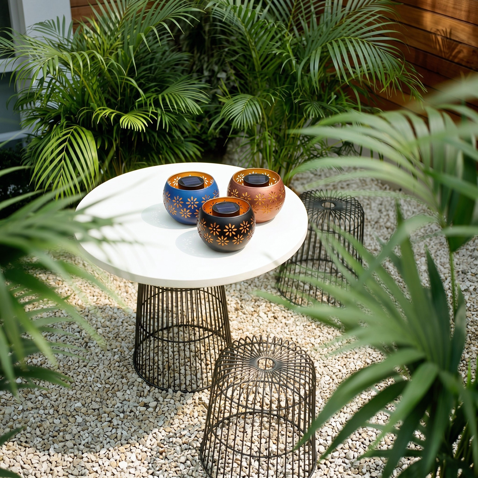Aldi's Belavi solar light fire bowls on a small table in a modern garden with foliage all around