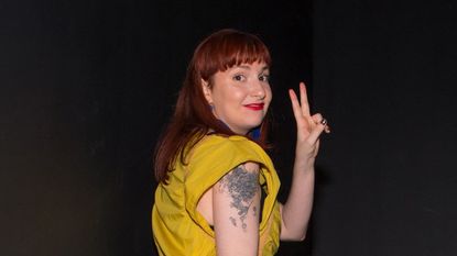 Lena Dunham raises two fingers to make the peace sign.