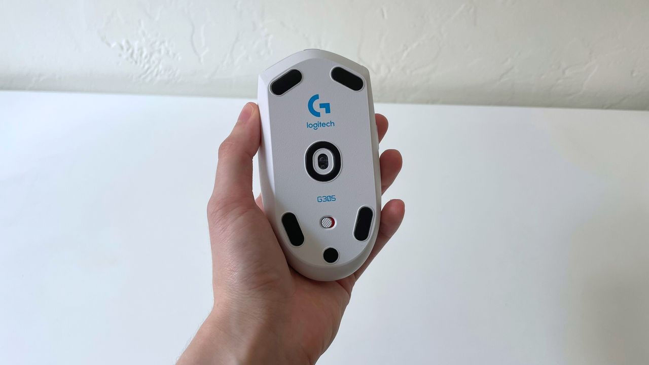 The Logitech G305 LIGHTSPEED in someone's hand with the bottom of the mouse visible