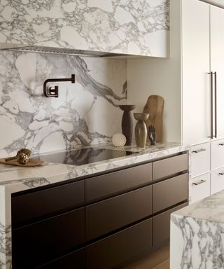 A marble kitchen with a pot filler, dark cabinets and bold veining