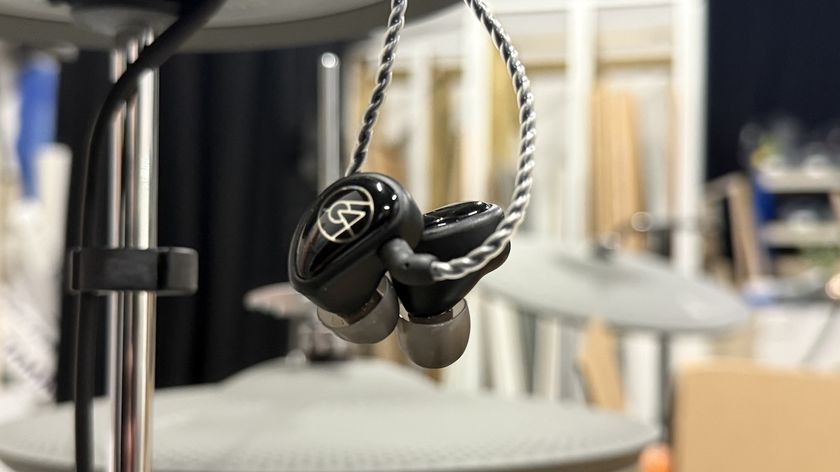 Pair of 64 Audio in-ear monitors hanging from a hi-hat cymbal