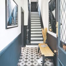 A small narrow hallway with two-toned walls and a dado rail with complementing Victorian star tiles