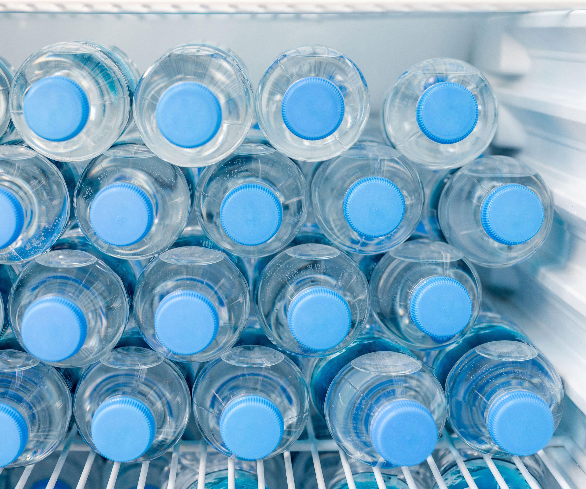 small plastic bottles of water in freezer compartment of fridge