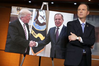 Rep. Adam Schiff stands before photo of Trump and Lavrov
