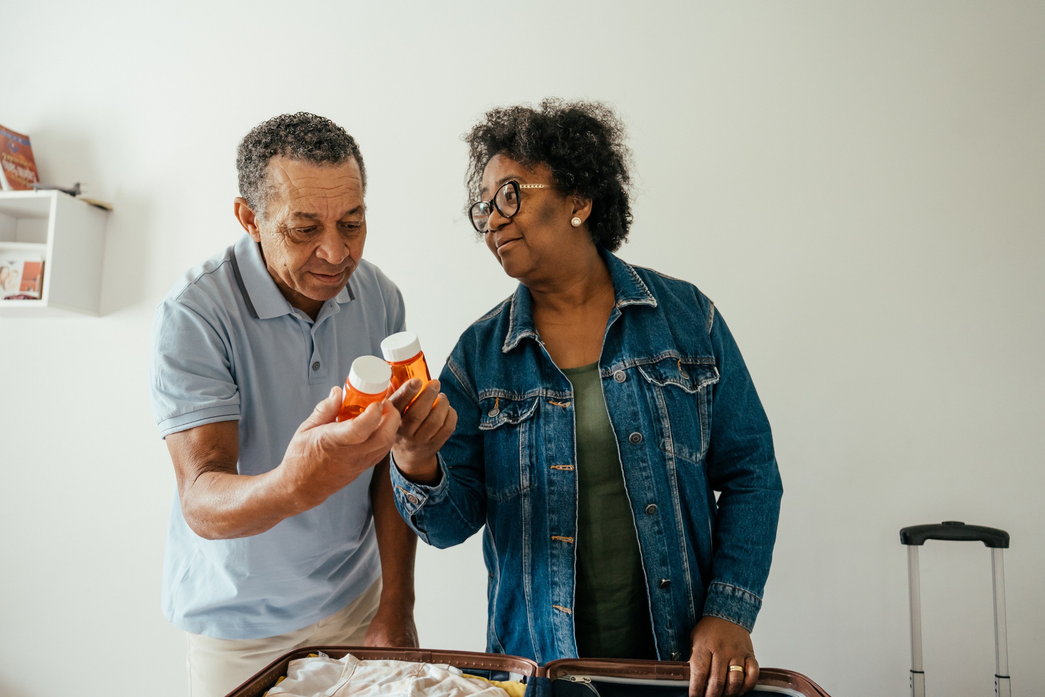 Elderly couple packing their suitcase in their bedroom to go on a trip