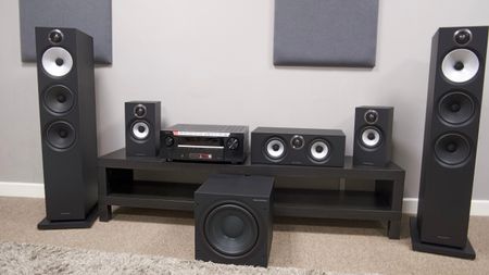 B&W 600 series speaker system and Denon AVC-3900H AV receiver on dark wood bench
