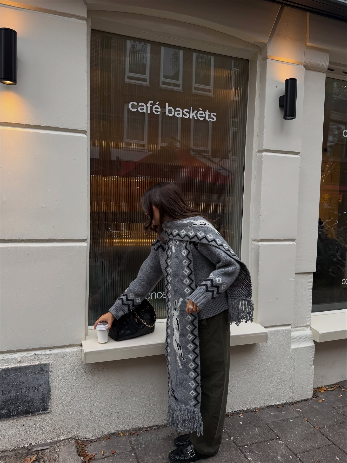 Woman wears a grey knit cardigan with matching grey knit scarf, khaki trousers and black loafers