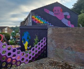 The wall of a house painted with a robot and a honeycomb structured purple wall