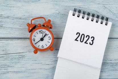 Calendar desk 2023 is the month for the organizer to plan and deadline with an alarm clock on a wooden table background
