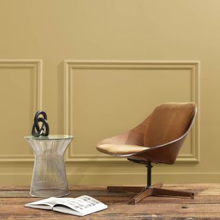 gold painted wall with tan swivel chair and side table