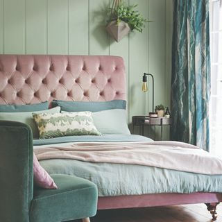 A sage-painted bedroom with a pink bed and panelled walls