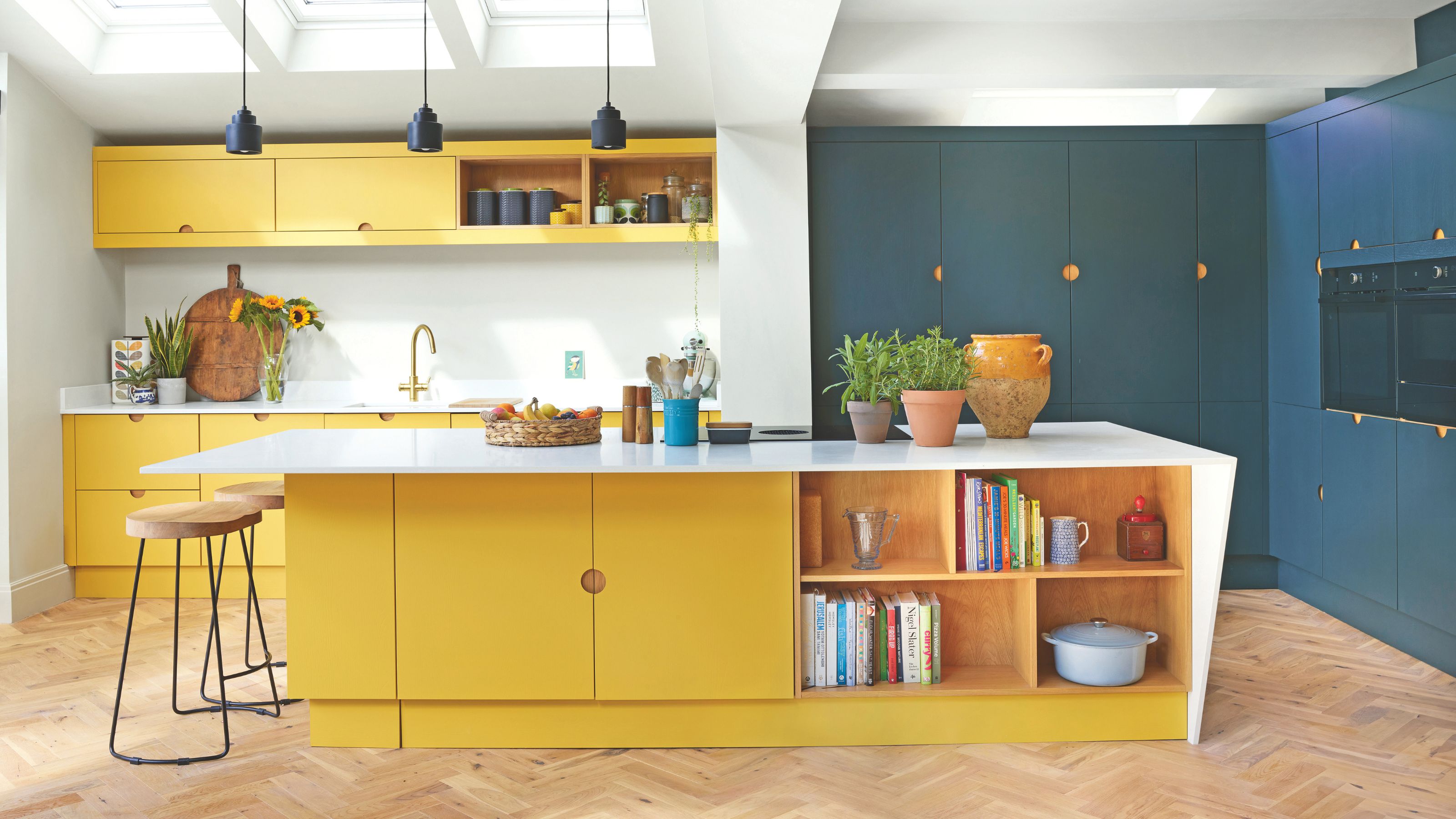 White painted kitchen with a mixture of yellow and dark blue cabinets, and a yellow kitchen island