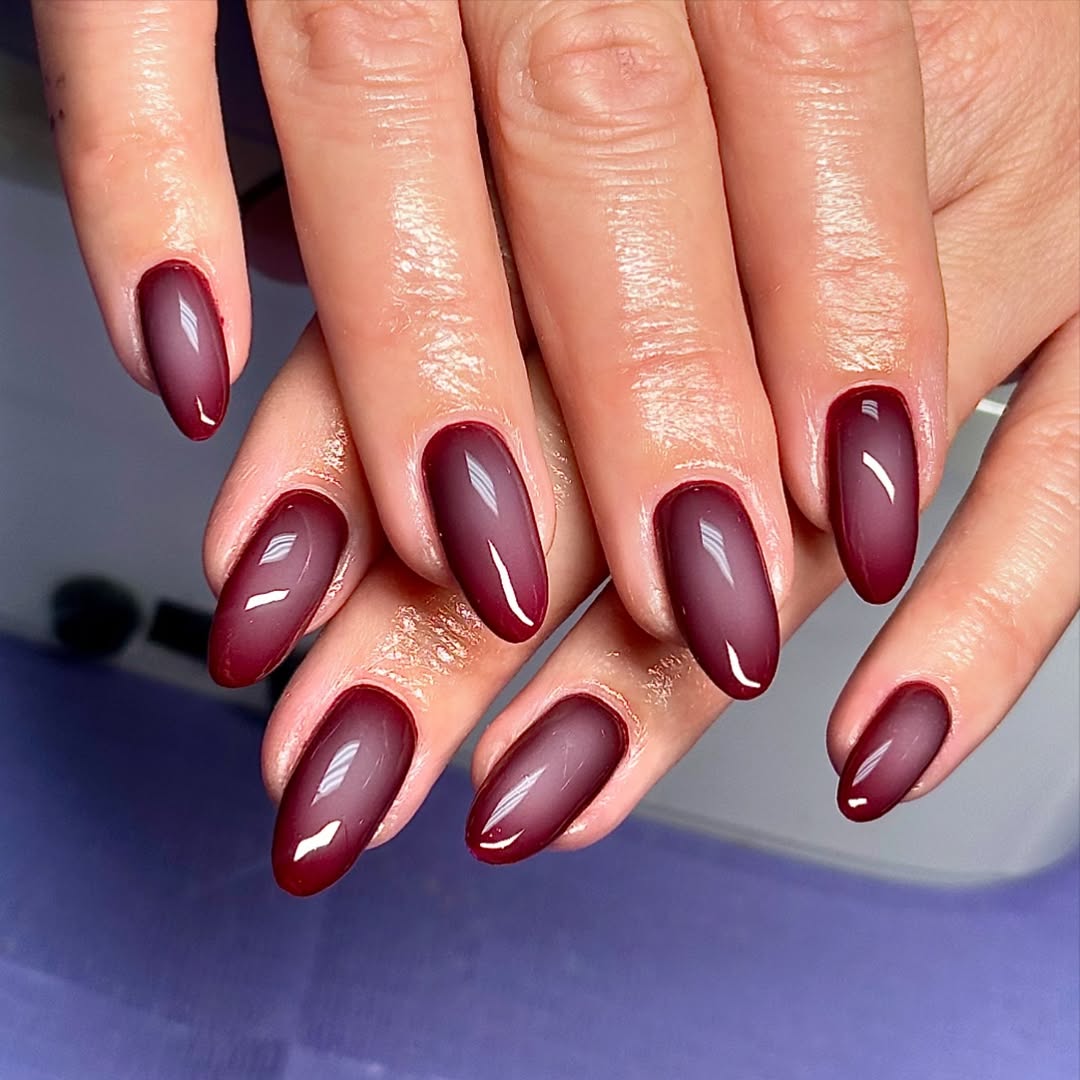 a person wearing a dark red manicure with a blurry aura design