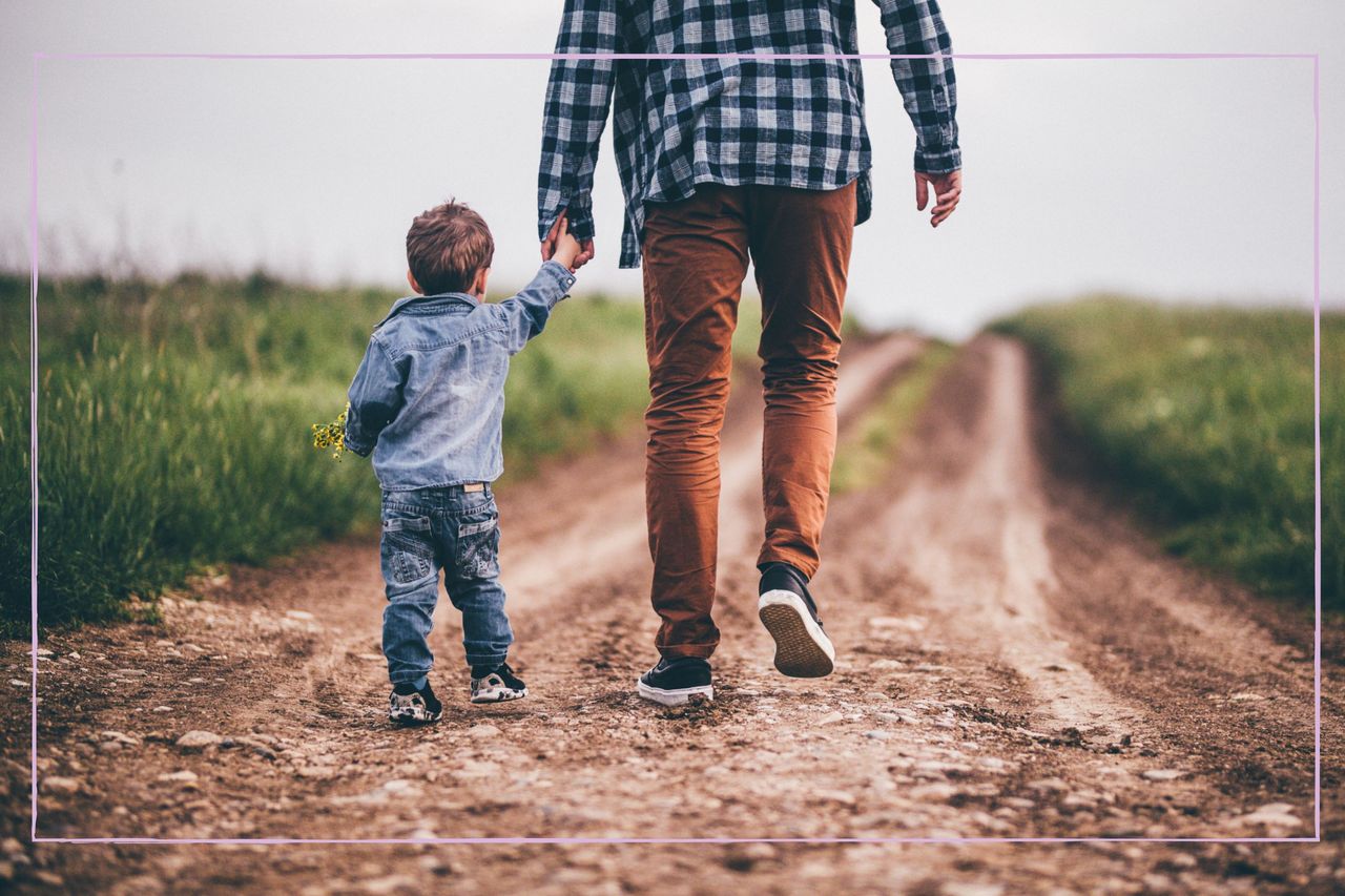 Man holding small child&#039;s hand and leading him away down a quiet path