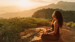 A woman doing yoga at sunset with mountain views