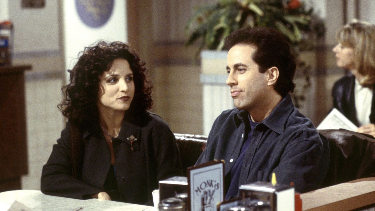 julia louis dreyfus and jerry seinfeld as elaine and jerry sitting at a diner in a still from seinfeld