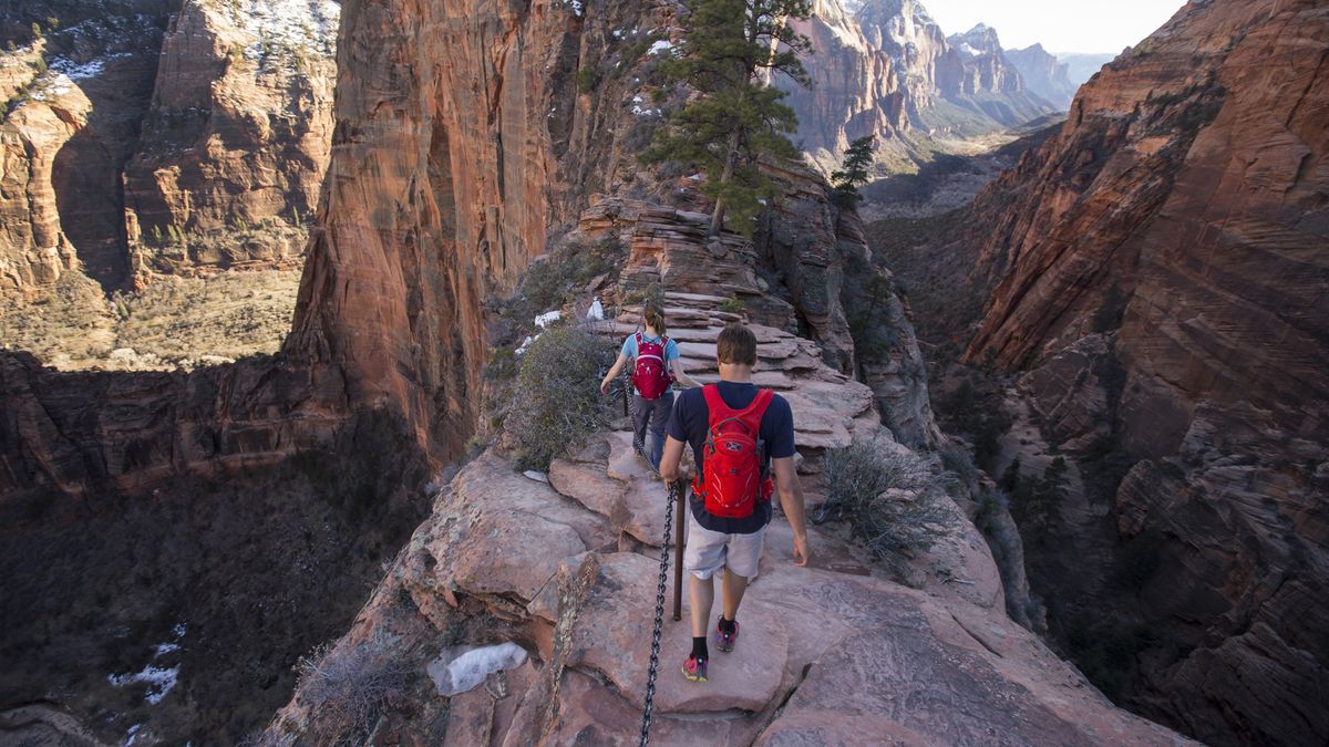 Hikers walk along the narrow fin of Angels Landing in Zion Utah