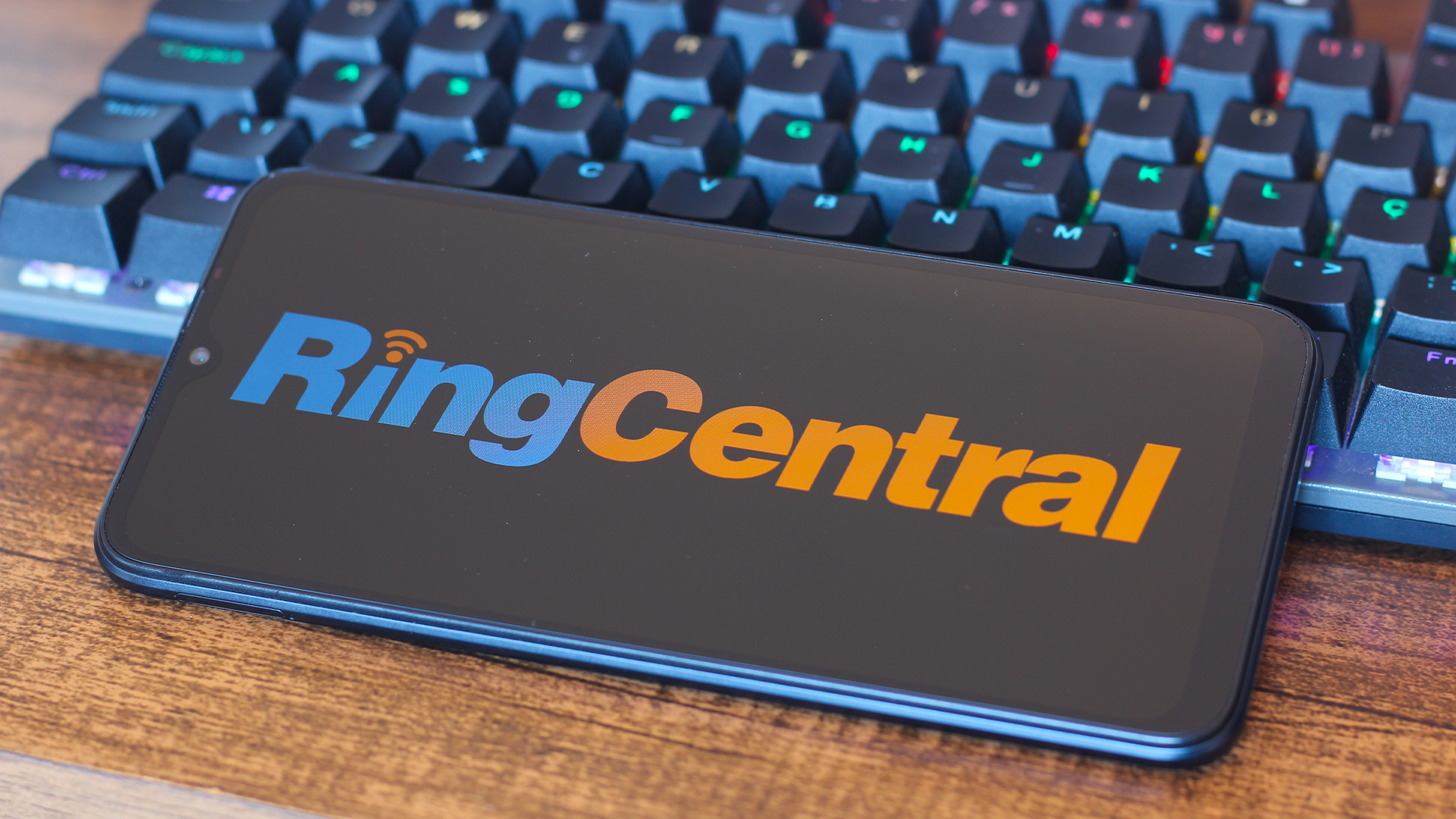 RingCentral logo and branding pictured on a smartphone screen placed on top of a desktop computer keyboard.