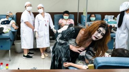 A staff member in a Halloween costume entertains volunteers donating blood at the Thai Red Cross Society's National Blood Centre in Bangkok.