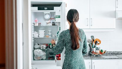 woman opening fridge in white kitchen