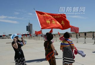 Crowds wave the Chinese flag as a Chinese Long March 2F rocket carrying the Shenzhou 9 spacecraft rolls out to the launch pad at Jiuquan Satellite Launch Center in northwest China on June 9, 2012.