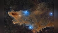 Colorful nebula with dense orange and blue gas clouds surrounding bright stars in deep space