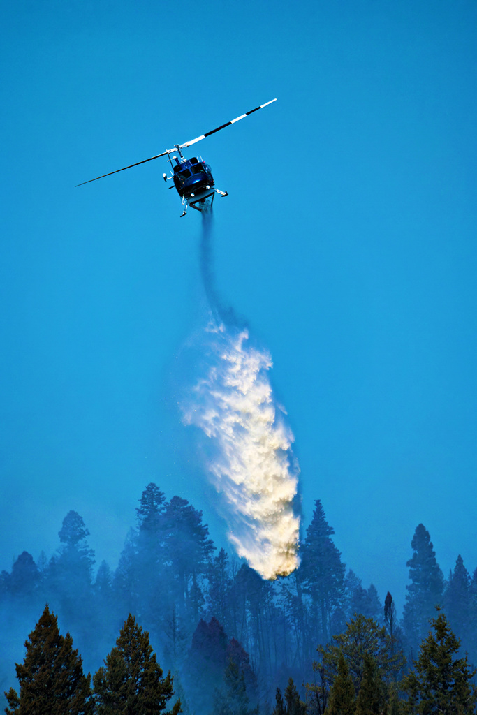 Helicopter dropping water on wildfires in Canada