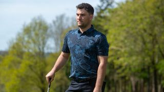 A golfer looks on whilst wearing a TravisMathew Mainlanders Polo