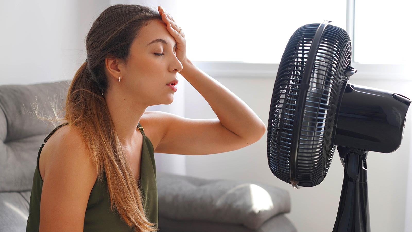 A woman struggling in a heatwave in front of a fan