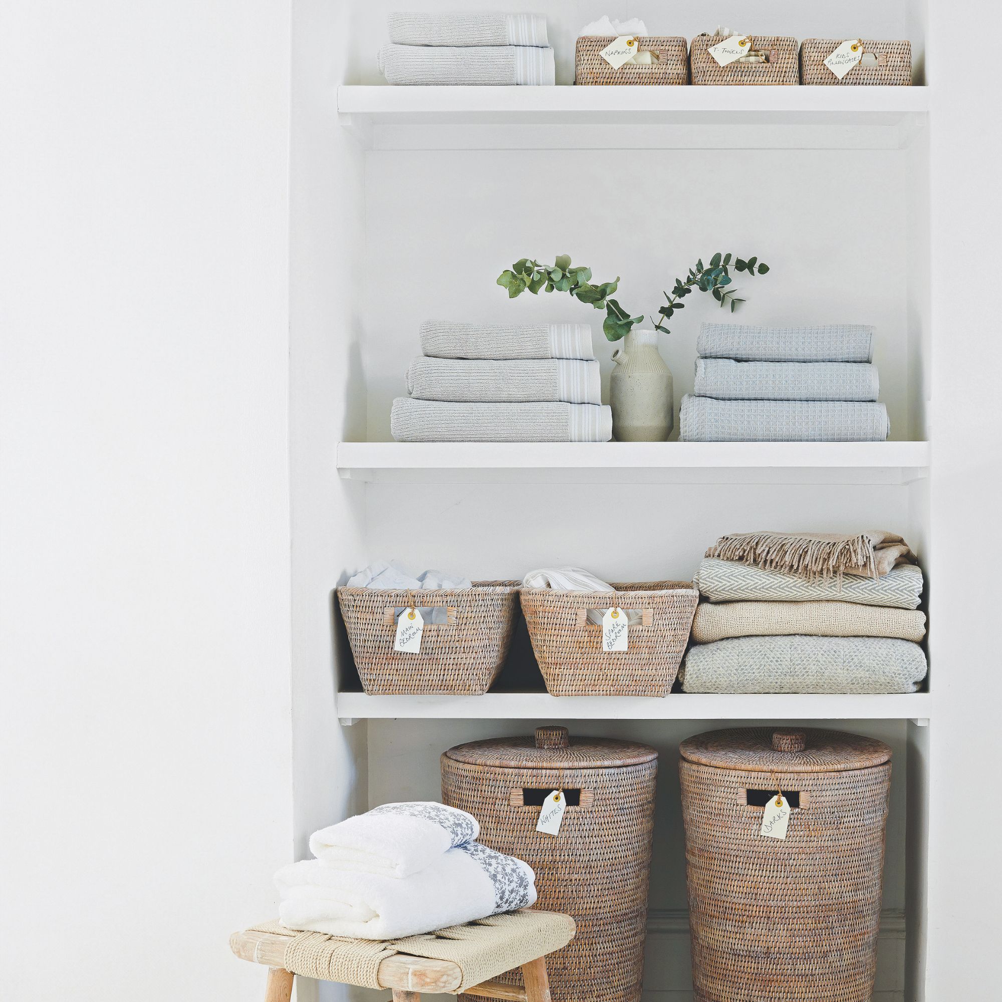 Two laundry baskets with shelves above filled with towels and blankets