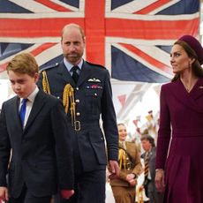 Prince George walking in front of Prince William and Prince Kate and a Union Jack flag