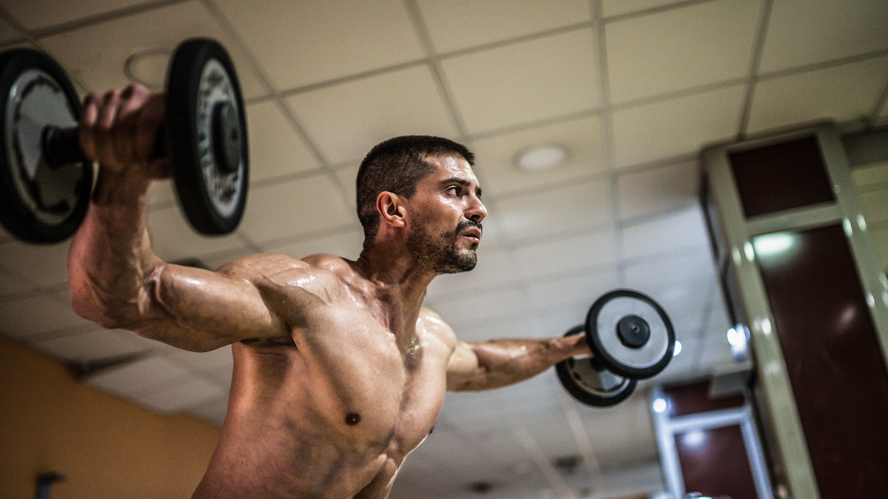 Man doing lat raises with a pair of dumbbells